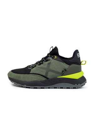 Sports shoe with a black mesh upper, green suede accents, and a thick black sole. Features yellow laces and a contrasting lime green heel.