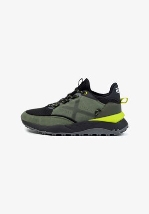 Scarpa sportiva con una tomaia in rete nera, accenti in suede verde e una suola nera spessa. Presenta lacci gialli e un tallone verde lime a contrasto.