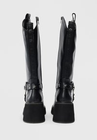 Melnas ādas ceļa auguma zābaki ar masīvu papēdi, ar dekoratīvu jostu ar zvaigžņu akcentiem un rāvējslēdzēju aizmugurē.