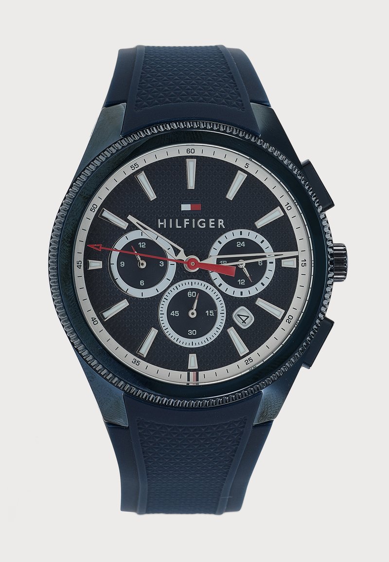 Μαύρο ρολόι χειρός Tommy Hilfiger με τρεις βοηθητικούς δείκτες, κόκκινη δεύτερη δείκτη, λευκούς δείκτες ώρας και υφασμένο μαύρο λουράκι από καουτσούκ.