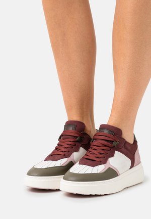 Sneakers with a white leather toe, burgundy suede upper, and olive green accents; thick white sole; round laces; perforated detailing.