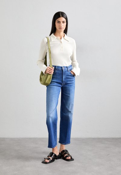 Ribbed cream long-sleeve top with button placket, blue straight-leg jeans, and black strappy sandals. Olive green shoulder bag.