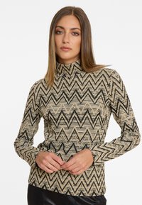 Musteriertes Langarm-Turtleneck-Top in Beige und Schwarz. Verfügt über ein Zickzack-Design mit einem texturierten Stoff. Enganliegender Schnitt mit hohem Kragen.