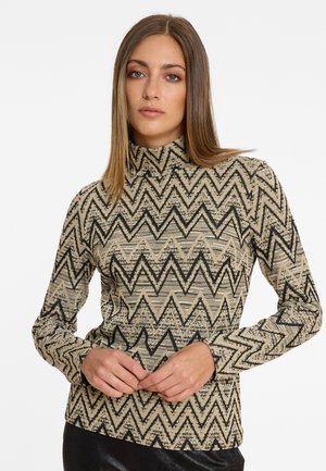 Haut à col roulé à manches longues imprimé en beige et noir. Présente un design en zigzag avec un tissu texturé. Style ajusté avec un col haut.