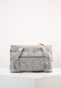 Borsa a tracolla in pelle grigia con spallacci e una tasca con zip frontale, posizionata su una superficie bianca contro uno sfondo bianco semplice.