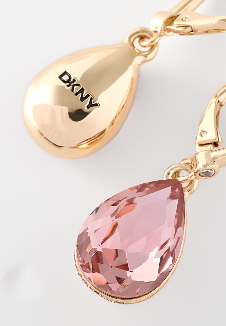 Goldfarbene Tropfenohrringe mit einem pinken, facettierten Tränenstein mit glatter Oberfläche und dem eingravierten "DKNY" auf dem oberen Teil.