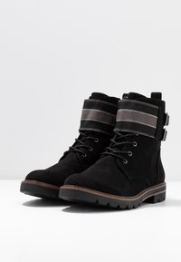 Stivali alla caviglia in suede nero con punta rotonda, caratterizzati da un risvolto a righe grigie e dettagli in metallo argentato, suola in gomma robusta e design con lacci.