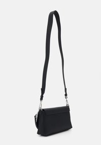 Bolso bandolera negro con textura lisa, forma rectangular, correa ajustable y herrajes de tono plateado. Detalle de cierre con solapa frontal.