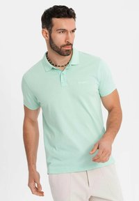 Polo shirt verde chiaro in cotone, con colletto classico, maniche corte e un logo ricamato discreto sul petto.
