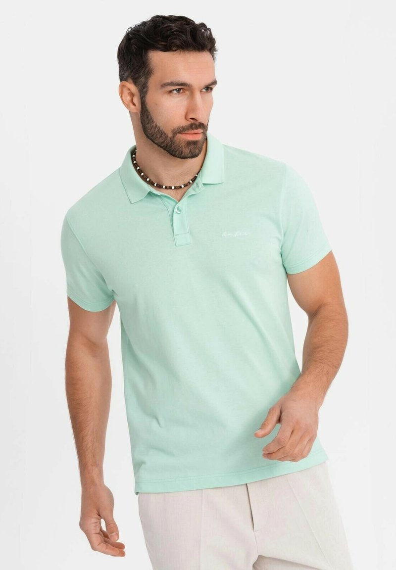 Polo shirt verde chiaro in cotone, con colletto classico, maniche corte e un logo ricamato discreto sul petto.