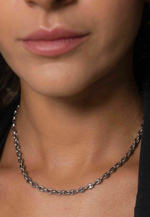 Zilveren ketting met ovale schakels en een gepolijste afwerking, rustend op de huid met een subtiele glans, close-up op de halslijn.