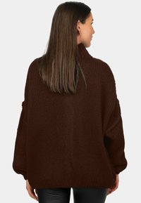 Pull en maille marron surdimensionné avec un col haut, une texture côtelée et des épaules tombantes, présenté de dos.