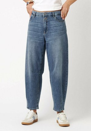 Mid-rise, relaxed-fit blue denim jeans with double button closure, worn with white sneakers and a white top.