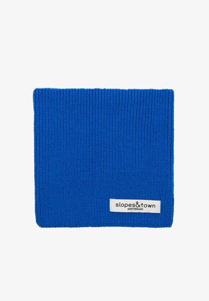 Blauer gestrickter Halswärmer mit gerippter Textur, versehen mit einem weißen Etikett, das "slopes&town AMSTERDAM" liest. Entworfen für Wärme und Komfort.