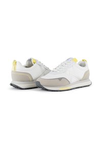 Baskets de sport blanches et grises avec une tige texturée, des accents jaunes et une semelle en caoutchouc noir. Présente un design à lacets et un tirant au talon.