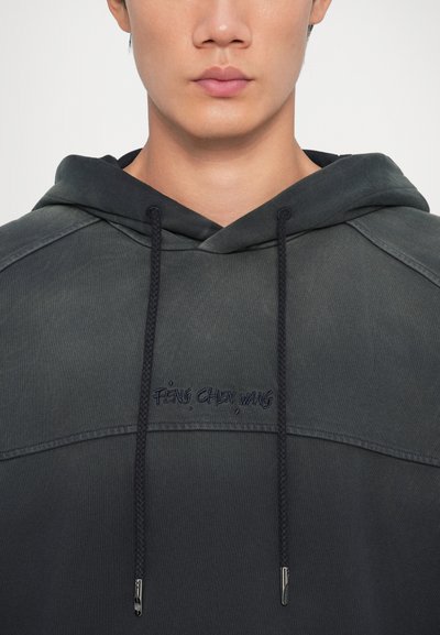 Sötét szürke kapucnis pulóver puha anyagból, kapucnival, vastag zsinegekkel és hímzett logóval a mellkason.