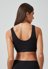 Schwarzer Sport-BH mit rundem Ausschnitt und breiten Trägern. Hergestellt aus weichem Stoff, zeichnet er sich durch eine glatte Textur und eine enganliegende Form aus.
