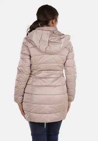 Giacca piumino beige con cappuccio, caratterizzata da sezioni trapuntate, una vestibilità su misura e un design di lunghezza media. Texture liscia e materiale leggero.