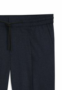 Navy blauwe jogger broek met een elastische tailleband en een trekkoord, zijzakken en een subtiele textuur afwerking.