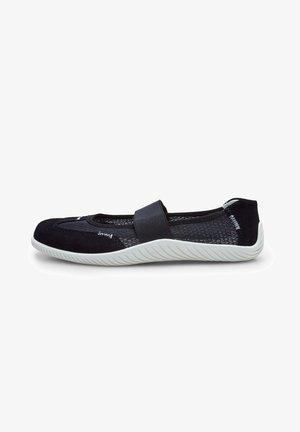 Zapato negro sin cordones con parte superior de malla, suela de goma blanca en contraste y una correa elástica decorativa. Presenta un diseño de punta redondeada.
