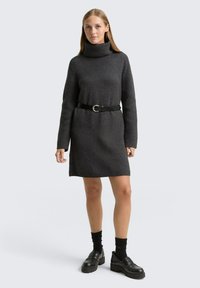 Robe pull en tricot gris foncé avec un col montant, des manches longues, et une ceinture noire ornée d'une boucle en métal argenté ronde. Texture lisse.