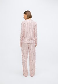 Set de pijamale cu dungi roz, cu mâneci lungi și pantaloni. Liniile verticale prezintă modele subtile. Material moale, cu croială lejeră.