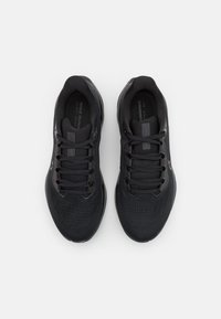 Chaussures de sport noires avec une tige en maille, des lacets en textile et une semelle rembourrée. Présente un branding subtil et un design épuré.