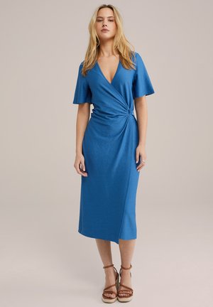 Robe bleue en tissu texturé ; elle présente des manches courtes, un décolleté en V profond et un détail noué à la taille. Longueur mi-mollet.
