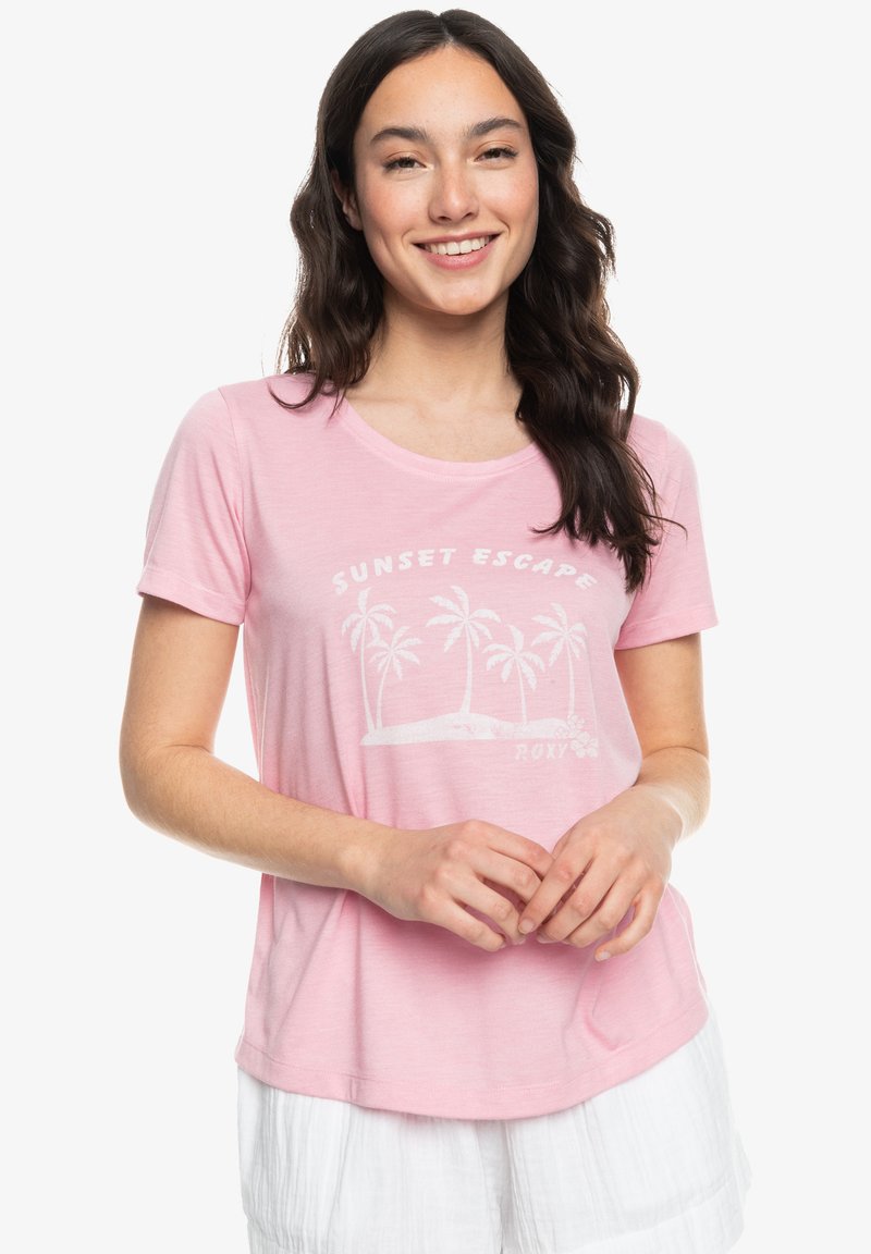 Lichtroze t-shirt met een ronde halslijn, korte mouwen en een witte grafische afbeelding met palmbomen en de tekst "SUNSET ESCAPE". Zachte textuur.