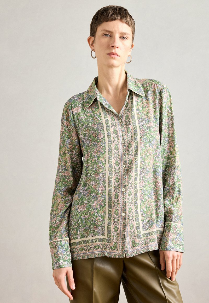 Πουκάμισο με μακριά μανίκια και κουμπιά σε πράσινο χρώμα με λουλουδάτα μοτίβα, διαθέτοντας διακοσμητική περιθώριο μπροστά και μυτερό γιακά. Λείο υφασματικό υλικό.