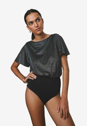 Schwarzer hoch taillierter Bodysuit kombiniert mit einem kurzärmligen, metallischen, anthrazitfarbenen Oberteil mit einem drapierten Ausschnitt und einer weichen Textur.