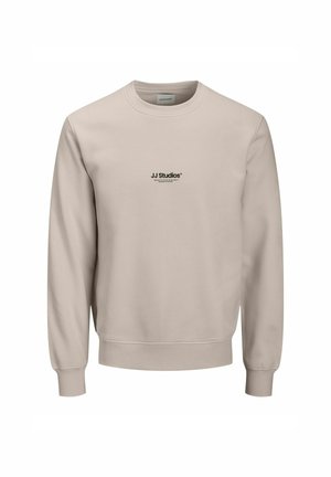 Beige langærmet sweatshirt med rund halsudskæring og lille sort "JJ Studios" logo centreret på brystet.