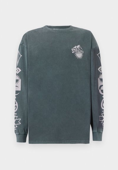 Μακρυμάνικη μπλούζα από σκούρο πράσινο βαμβάκι, με λευκά γραφικά σχέδια στις μανίκες και το στήθος. Ριμπάριστος λαιμός και μανσέτες. Τυπική εφαρμογή.