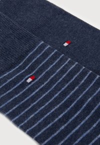 Marine sokken met een effen bovenstuk en een gestreept ontwerp in verschillende tinten blauw, met een klein logo in rood, wit en blauw.