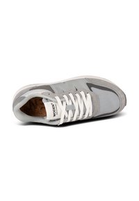 Scarpa atletica grigia realizzata con materiali in rete e suede, con lacci bianchi, soletta in sughero e logo sulla linguetta. Design elegante e arrotondato.