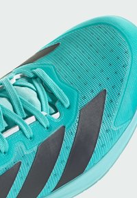 Tyrkysová sportovní bota s síťovaným svrškem, černými akcenty a texturovaným povrchem. Obsahuje tkaničky a výrazné logo na boku.