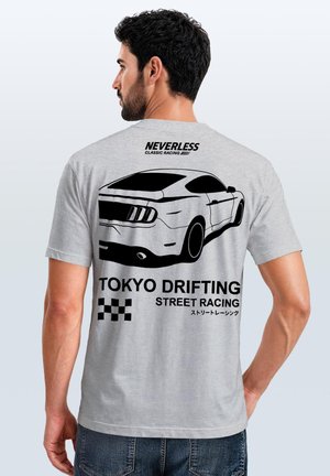 Man wearing gray t-shirt with black car graphic and text reading "Neverless Classic Racing" and "Tokyo Drifting Street Racing" on the back.