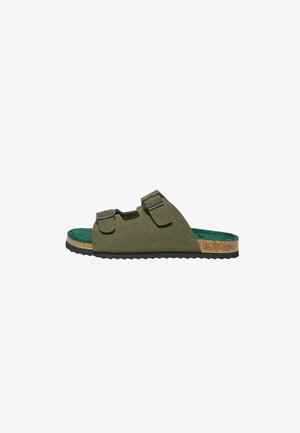 Sandale slide en daim vert olive avec deux brides réglables à boucle, semelle intermédiaire en liège, semelle intérieure verte et semelle extérieure en caoutchouc noir rainurée.