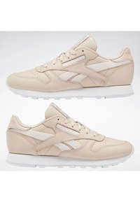 Paire de baskets en cuir beige Reebok avec semelle blanche et logo, vues de profil gauche et droit sur fond blanc.