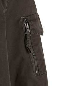 Schwarze Stoff-Cargo-Hosen mit einer seitlichen aufgesetzten Tasche und einem Reißverschluss. Das Material ist glatt mit matter Oberfläche.