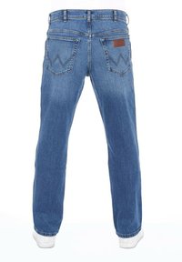 Jeans de mezclilla azul con corte recto, que cuentan con dos bolsillos traseros y un parche de cuero marrón. Tejido texturizado con un ligero desgaste.