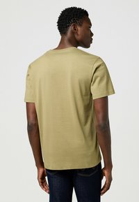 Olivi vihreä puuvillapaita lyhyillä hihoilla ja pyöreällä kaula-aukolla, jossa on sileä pinta ja rento leikkaus, esitetty takaa.