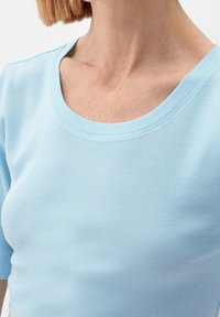 Ljusblå kortärmad t-shirt med vid ringning, tillverkad av mjukt bomullstyg; slät yta och minimala sömnadsdetaljer.