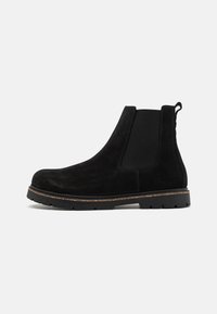 Les bottines chelsea en daim noir présentent des panneaux latéraux élastiques, une semelle en caoutchouc épaisse et une languette pour un enfilage facile. La finition texturée offre une bonne adhérence.