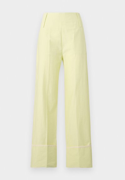 Pantalon large en tissu jaune pâle avec une texture lisse. Dispose d'une taille haute et d'une couture contrastante le long de l'ourlet.