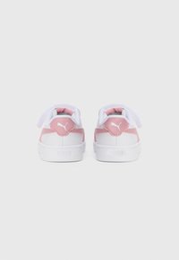 Zapatillas blancas con un acento rosa en el talón, material de cuero suave, punta redonda y suela de goma texturizada con cordones.