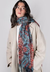 Bufanda con estampado floral en tonos azul verdoso y óxido, fabricada en tejido suave, con bordes con flecos e intrincados motivos animales.
