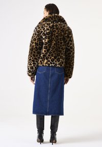 Chaqueta de piel sintética de estampado de leopardo con un gran cuello, combinada con una falda de mezclilla y botas negras altas hasta la rodilla. Textura suave y coloración vibrante.