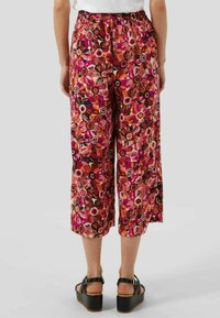 Culottes à imprimé floral en rose, rouge et noir, dotées d'une taille élastique et d'une coupe jambes larges, confectionnées dans un tissu léger.