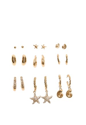 Siedem par kolczyków w złotym odcieniu, w tym sztyfty, koła, rozgwiazdy oraz wzory spiralne, niektóre z ozdobami z cyrkonii.